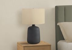 a nightstand with a lamp on top of it next to a night stand and bed