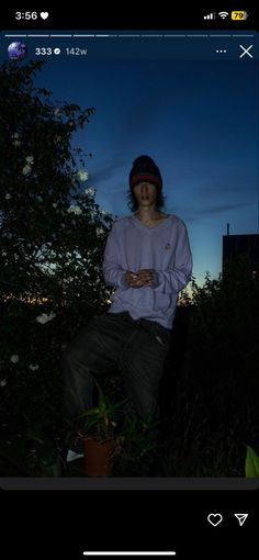 a man sitting on top of a tree next to a plant in the night time