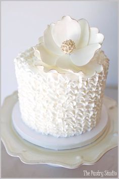 a white frosted cake with flowers on top is sitting on a plate and sits on a table