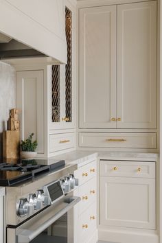 a stove top oven sitting inside of a kitchen next to white cupboards and drawers