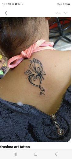 the back of a woman's neck with a tattoo design on her left shoulder