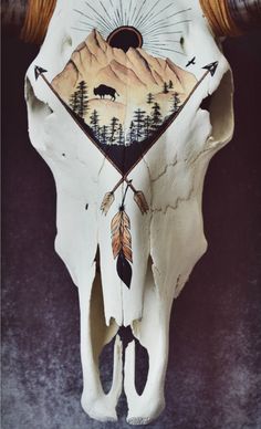 a cow skull with an arrow on it's back and mountains in the background