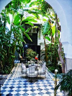 an outdoor dining area with potted plants and checkered tile flooring, surrounded by greenery