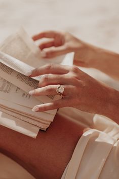 a woman's hand resting on top of a stack of papers and reading a book