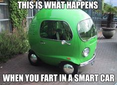 a small green car parked on the side of a road next to a planter