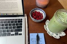 a laptop computer sitting on top of a wooden table next to a cup of coffee