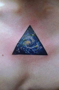 a woman's chest with a triangle and galaxy tattoo on her left side shoulder