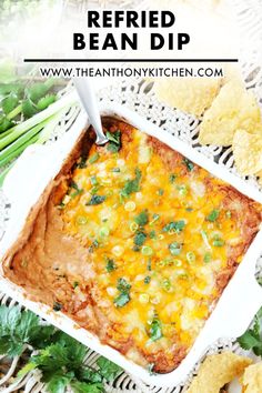 a white casserole dish filled with mexican food and tortilla chips on the side