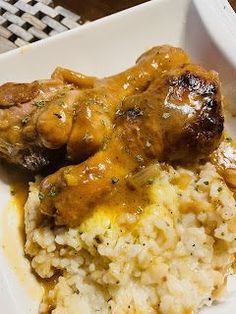 a white plate topped with meat and rice covered in gravy