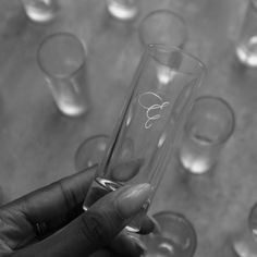 a person holding a wine glass in front of many glasses on a table with one hand