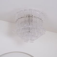 a glass chandelier hanging from the ceiling in a room with white walls and ceilings