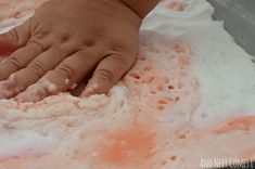 a child's hand on top of flour in a bowl with pink and white colors