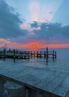 the sun is setting at the end of the pier