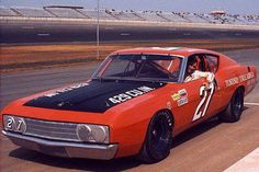 an orange and black car driving down a race track