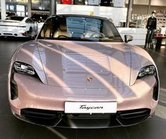 the front end of a pink sports car in a showroom