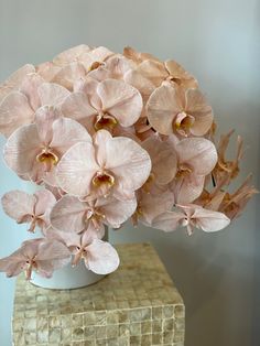 a white vase filled with pink flowers on top of a table