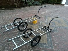 two bikes sitting on the ground with one being pushed by a hand cart and another being pulled by a wheelbarrow