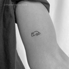 a black and white photo of a person's arm with a small mouse tattoo on it