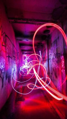 a long exposure photo of light painting in an alleyway with graffiti on the walls