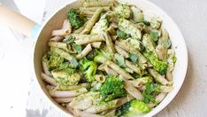 a bowl filled with pasta and broccoli on top of a white tablecloth