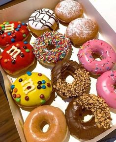 a box filled with lots of different flavored donuts on top of a table