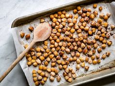 roasted chickpeas on a baking sheet with a wooden spoon