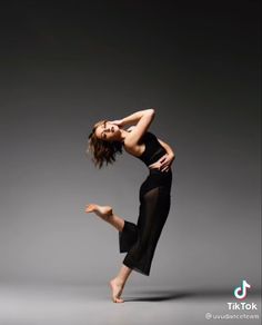 a woman in black is dancing on a gray background