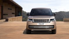 the new range rover is parked in front of a building with mountains in the background