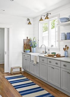 a kitchen with gray cabinets and white walls is featured in the magazine southern style home