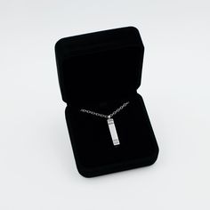 a necklace in a black velvet box on a white surface with a chain attached to it