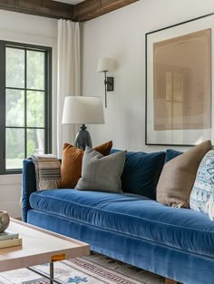 a living room with blue couches and pillows on top of the couch is next to a window