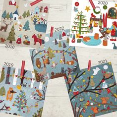 four different christmas cards on a white wooden surface with trees and houses in the background