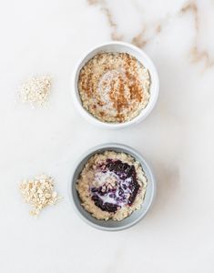 two bowls filled with oatmeal sitting on top of a white marble counter