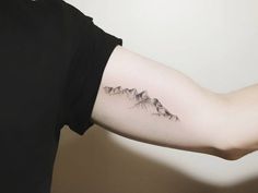 a person with a mountain tattoo on their arm