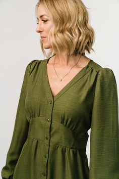 Casual and stylish all in one dress Lightweight linen-like material Olive green color V-neckline Buttoned placard down front of dress Gathering at bust, shoulder yoke, and across back Long sleeves with single buttons at cuffs Upturned, paneled V-waistband with subtle gathering underneath Elastic at back waist Unlined 63% Recycled Polyester, 37% Polyester Trina is 5'6, cup size 32D, size 2 and is wearing size S Linen Dress Button Down, Fall A Line Dress, Pretty Work Dresses, Winter Linen Dress, Long Sleeve Linen Dress, Flamboyant Natural Dress, Maxi Dress Dark, Button Midi Dress, Dresses For Fall