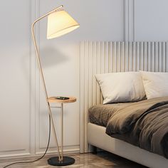 a lamp that is on top of a table next to a bed with pillows and blankets