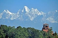 the mountains are covered with snow in the distance, and there is a clock tower at the top