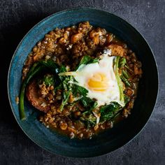 a blue bowl filled with food on top of a black table next to a knife and fork