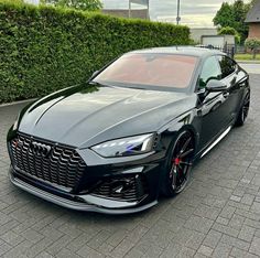 a black car parked in front of a hedge