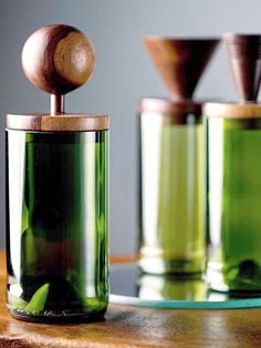 three green glass containers with wooden spoons in them sitting on a table next to each other