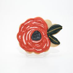 a cookie shaped like a flower with icing on it's petals and leaves