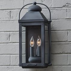 two candles are lit on an outdoor wall light