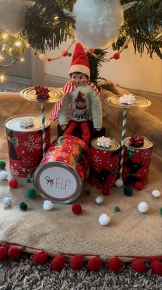 an elf is sitting in front of some tins and candy canes on the floor