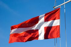 the danish flag is flying high in the blue sky royalty image - free stock photo