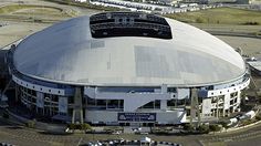 an aerial view of a stadium with cars parked in the parking lot and buildings around it