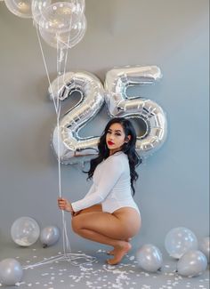 a woman is posing with balloons and the number twenty five