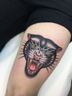 a black panther tattoo on the right arm and leg, with green eyes in it's mouth