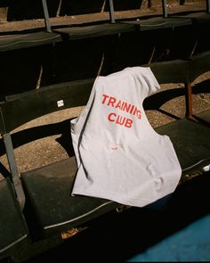 a t - shirt sitting on top of a bench in an empty stadium seat with the words training club printed on it