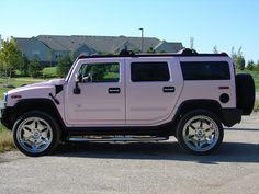 a pink hummer is parked on the side of the road in front of some houses