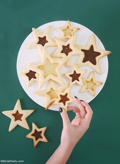 someone is decorating star cookies on a plate